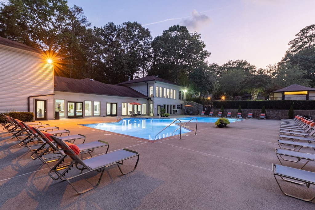 a swimming pool with chaise lounge chairs and a building in the background at Seven Pines, Alpharetta, GA