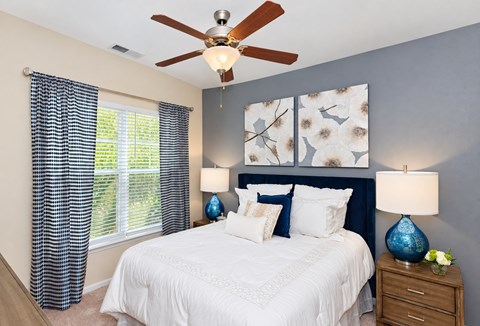 A bedroom with a white bed and a ceiling fan.