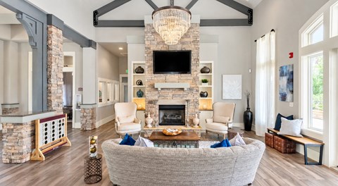 A living room with a grey couch and a stone fireplace.