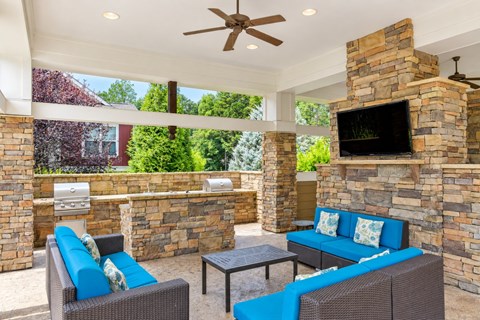 A patio with a blue couch and a stone fireplace.