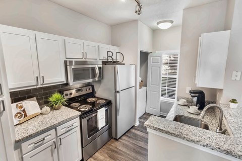 A kitchen with white cabinets and a granite countertop.