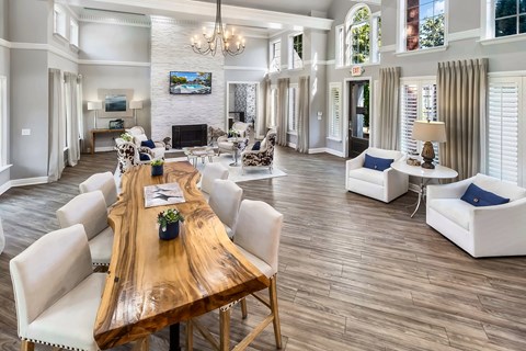 A large, well-lit living room with a wooden table and white chairs.
