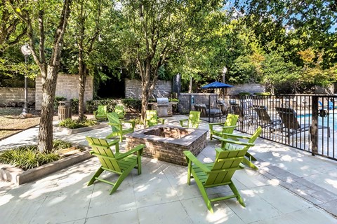 A patio with a fire pit and chairs.