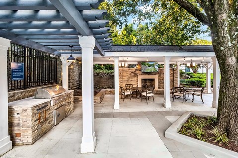 A covered outdoor patio with a fireplace and seating area.