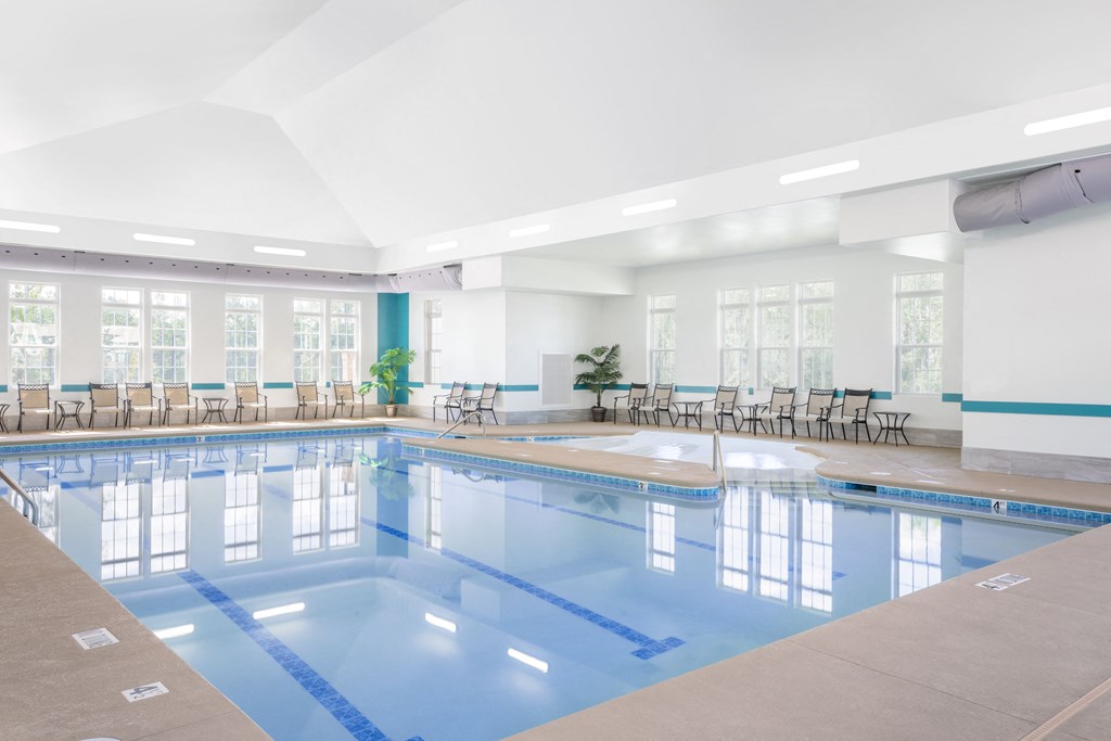 a large indoor swimming pool with chairs and tables around it