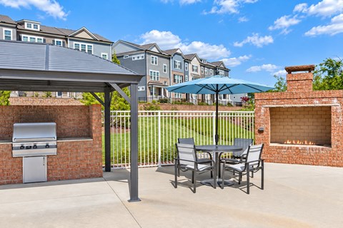 A patio with a grill and chairs under a canopy.