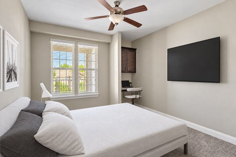 A bedroom with a bed, a ceiling fan, and a window.