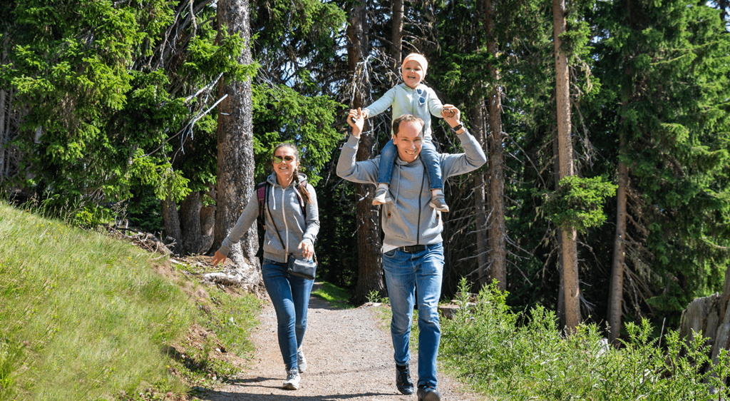 a man and woman walking down a trail with a child on their shoulders