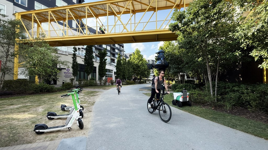 A person riding a bike under a yellow bridge in a park.