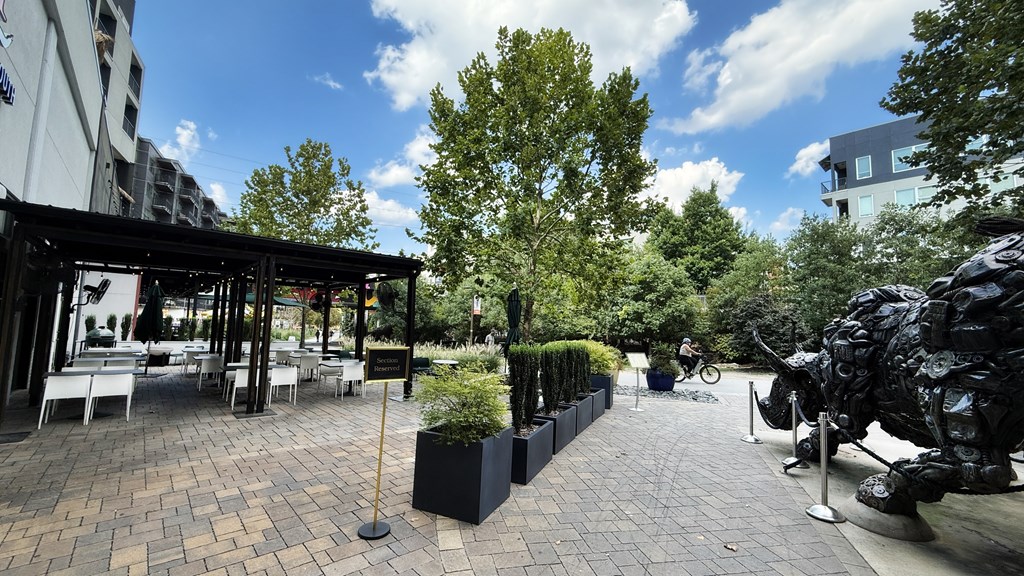 A sculpture of a black bear is on the right side of a paved walkway.