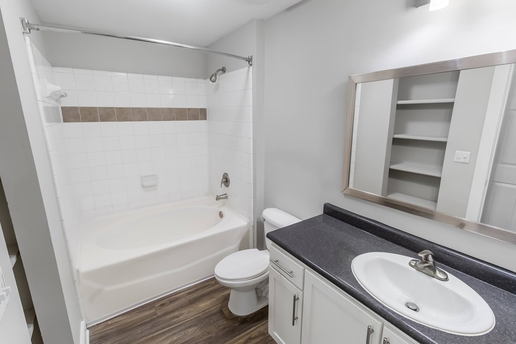 A white bathroom with a black counter top and a white toilet.