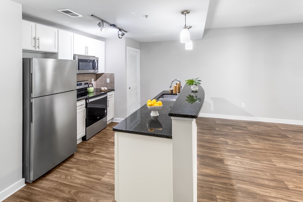 A kitchen with a refrigerator, microwave, oven, and sink.