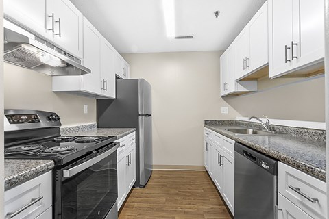 an empty kitchen with white cabinets and stainless steel appliances