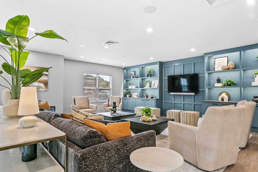 A living room with a grey couch, a white table, and a TV on the wall.