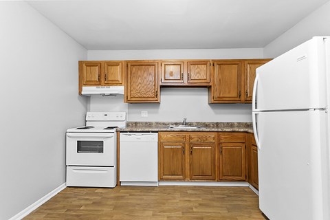 an empty kitchen with white appliances and wooden cabinets