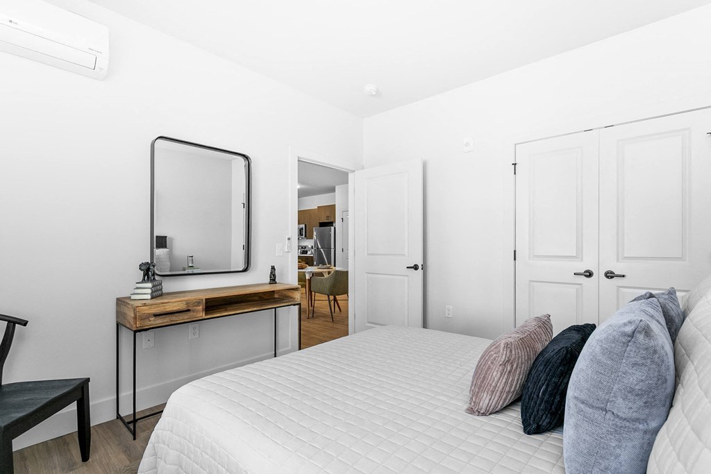 A bedroom with a bed, a desk with a mirror, and a chair.