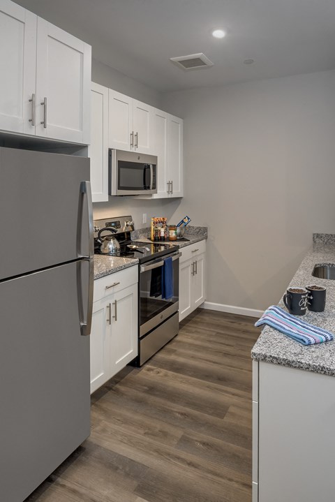 a kitchen with stainless steel appliances and white cabinets at Eden & Main 55+ Apartments, Southington, CT 06489