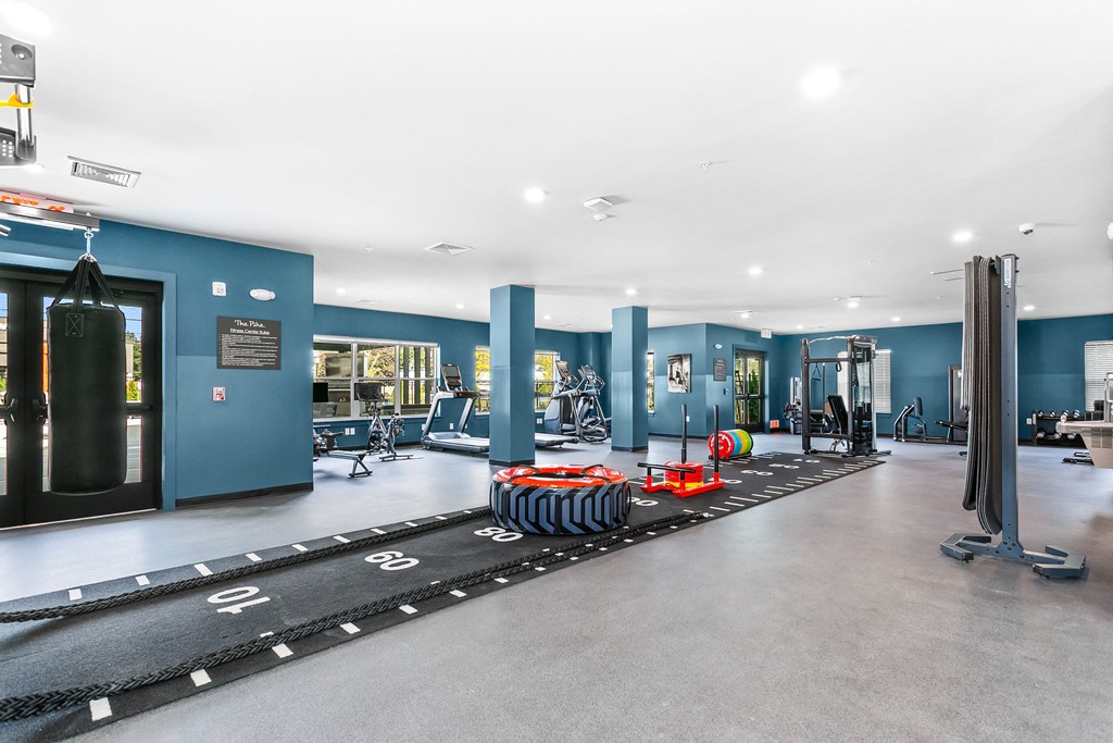 A gym with a black mat and orange weights on the floor.