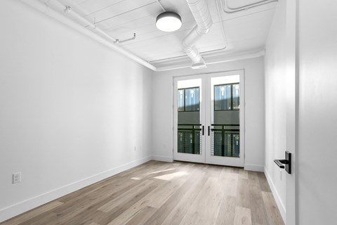 a living room with white walls and a door to a balcony