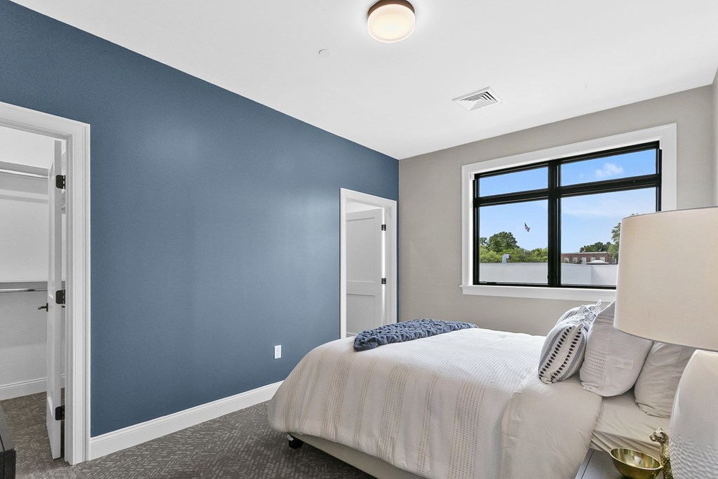 A bedroom with a bed, pillows, and a lamp.