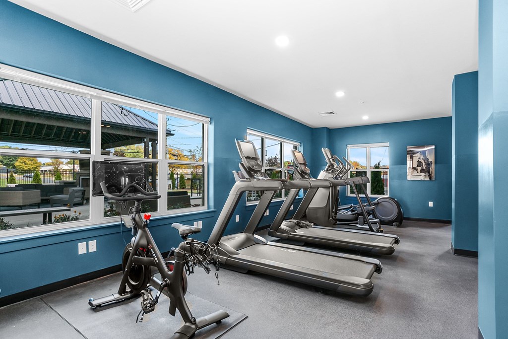 A gym with a row of treadmills and elliptical machines.
