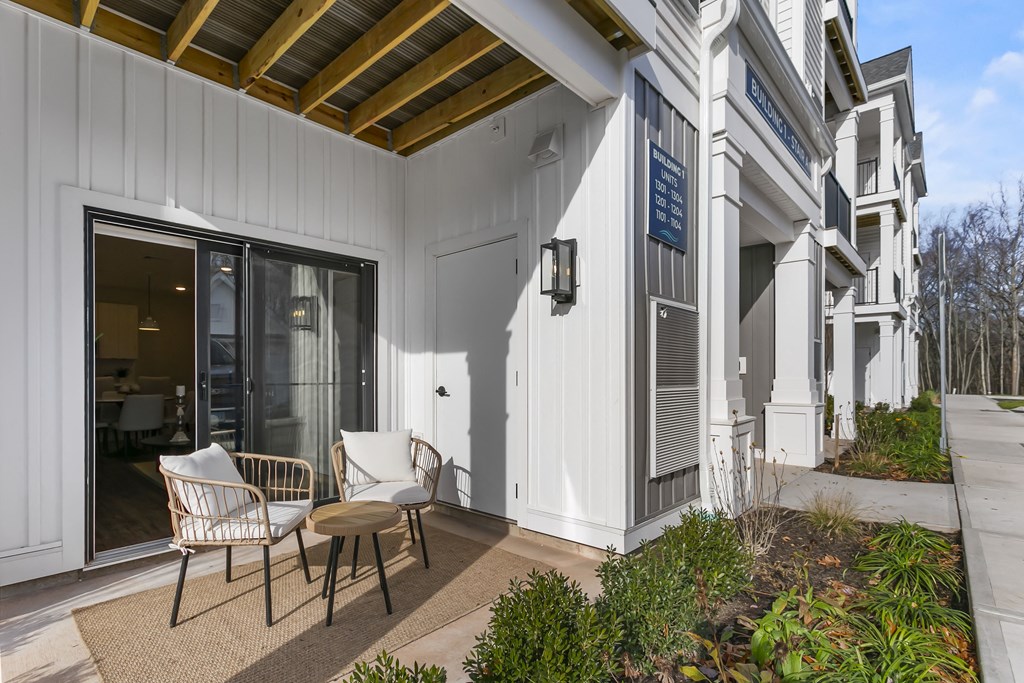 A white building with a porch and two chairs.
