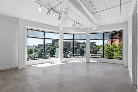 an empty living room with large windows and a city view