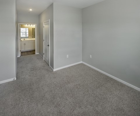 an empty room with a carpeted floor and a door to a bathroom at Eden & Main 55+ Apartments, Southington , Connecticut