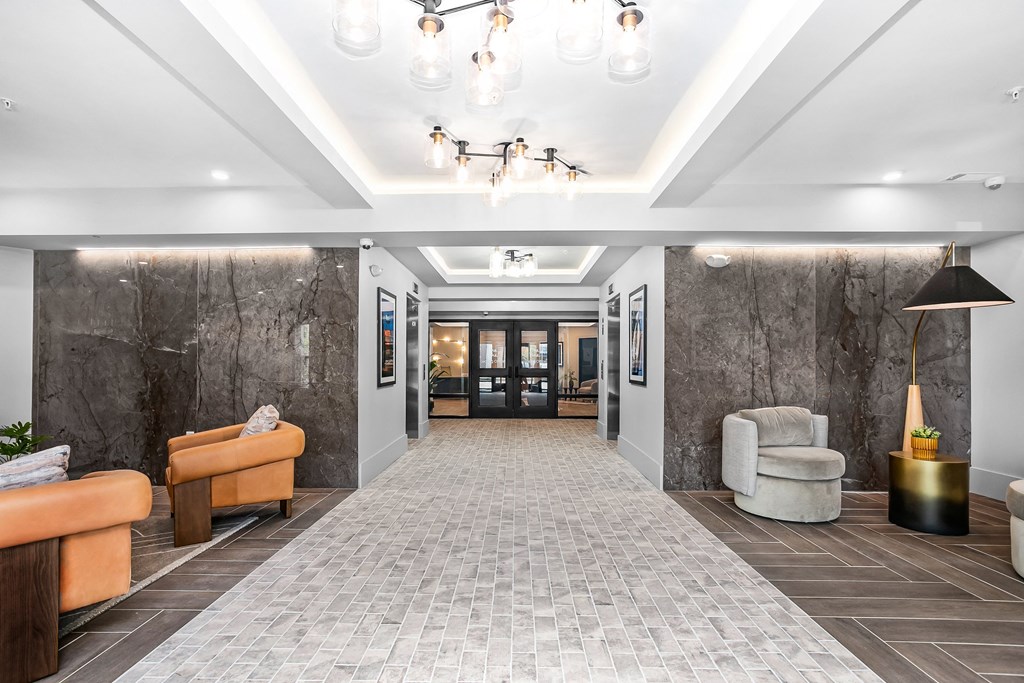A spacious lobby with a marble wall and a tiled floor.