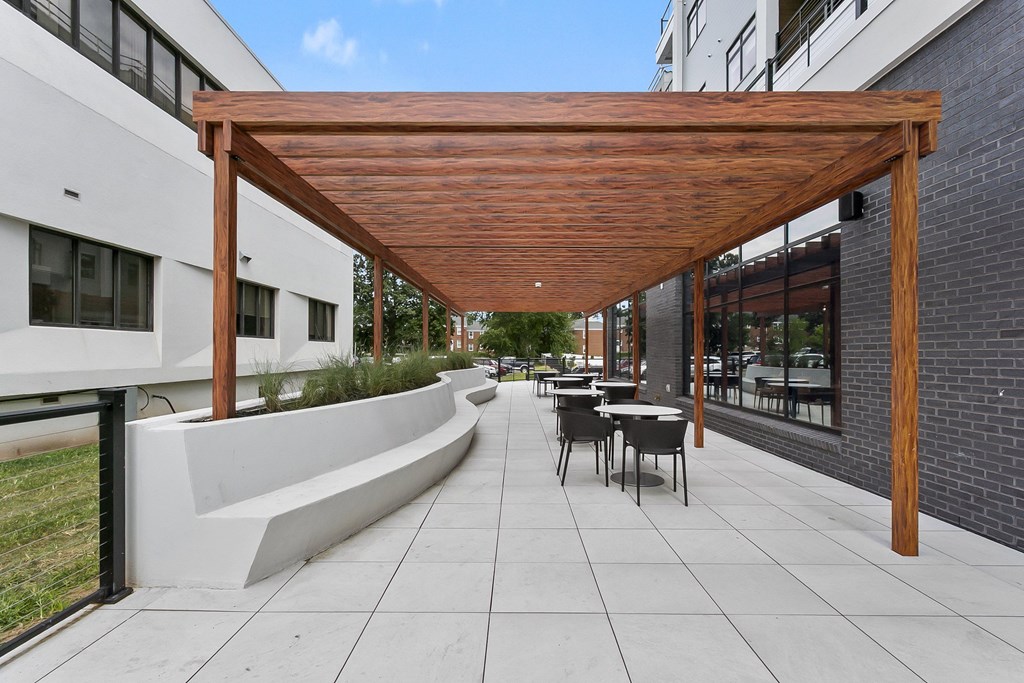 A patio with a wooden pergola and a white bench.