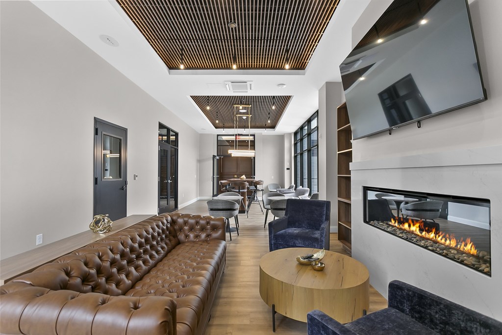 A modern living room with a brown leather couch and a fireplace.