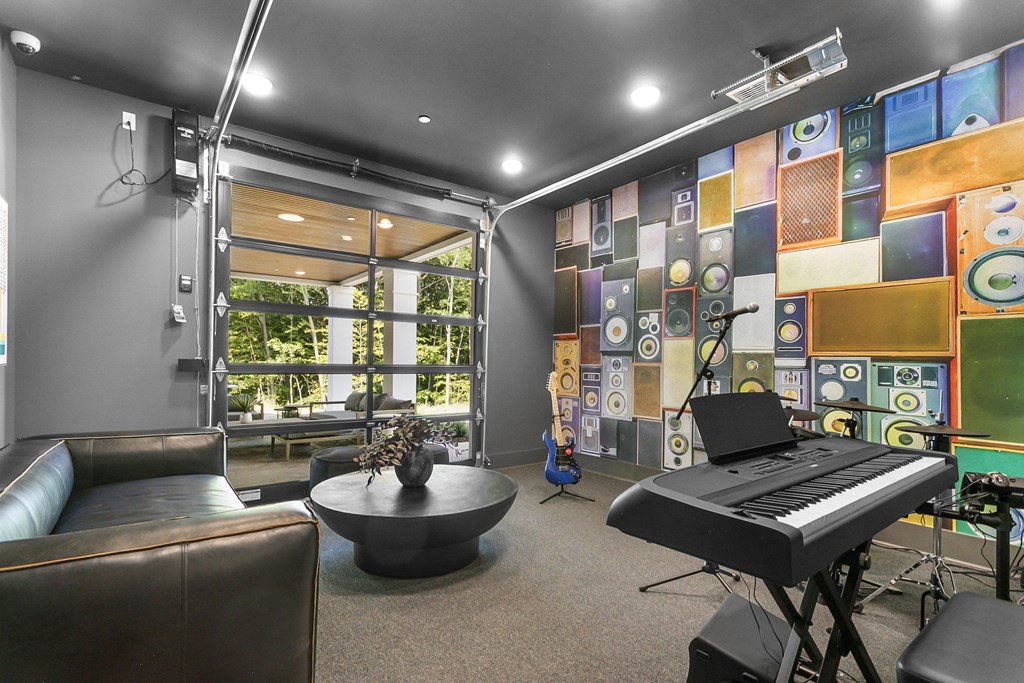 A room with a piano, a couch, and a wall of speakers.