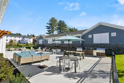 A patio area with a table and chairs and a green umbrella.