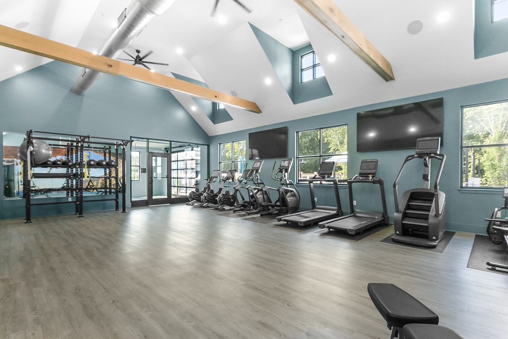 A spacious gym with a variety of equipment including treadmills, weights, and a bench.
