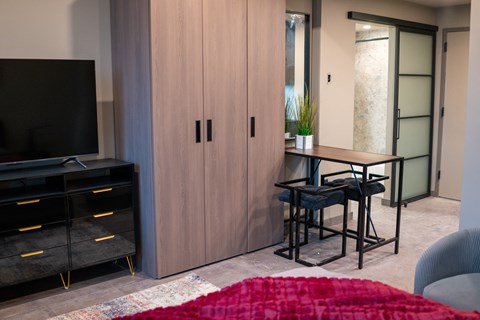 A modern living room with a red rug and a black television.