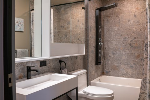 A modern bathroom with a sink, toilet, and bathtub.