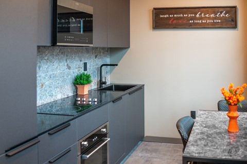 A modern kitchen with a grey cabinet and a quote on the wall.