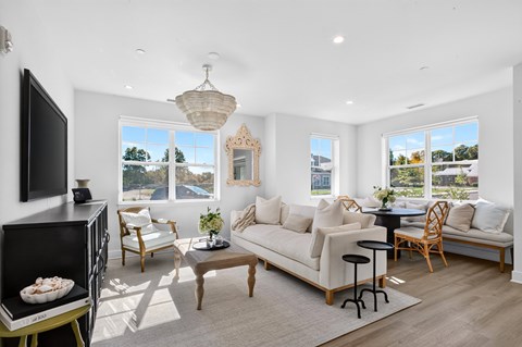A living room with a white couch, a coffee table, and a television.