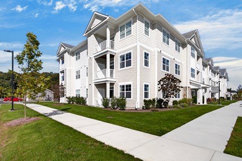 A white two-story apartment building with a green lawn in front.