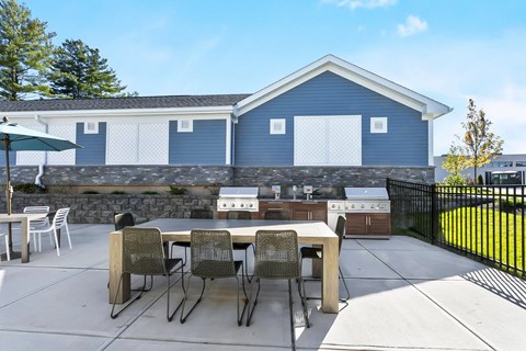 A blue house with a white fence and a patio with chairs and a table.