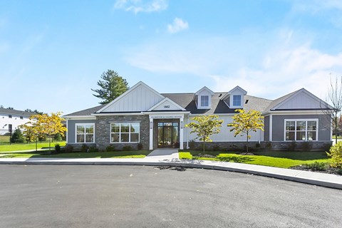 A grey house with a white fence and a tree in front.