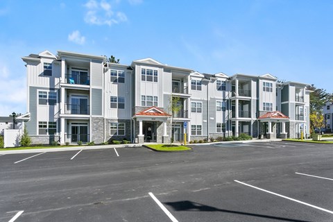 A large apartment complex with a parking lot in front.