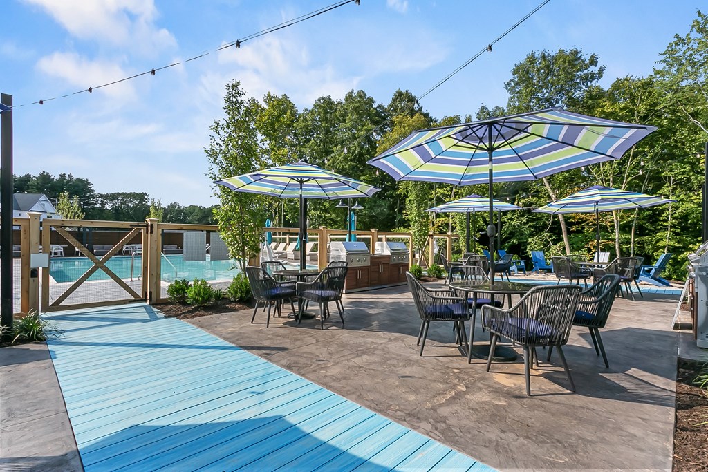 A patio with tables and chairs under umbrellas.