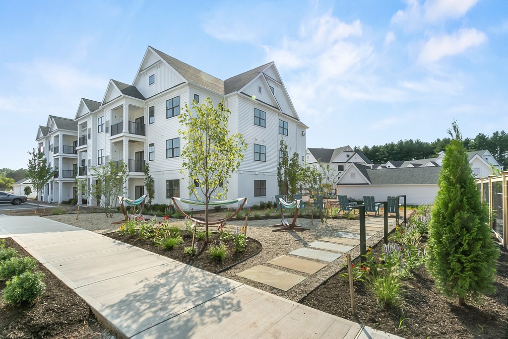 A white two-story house with a front yard and a playground.