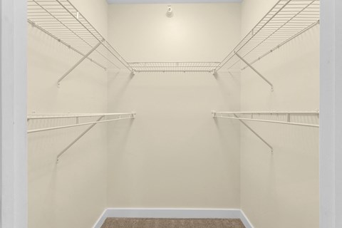 a spacious walk in closet in a home with white walls and empty shelves