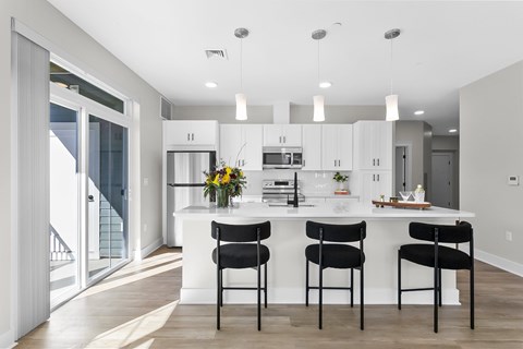 Modern and spacious kitchen with a white island and black chairs.