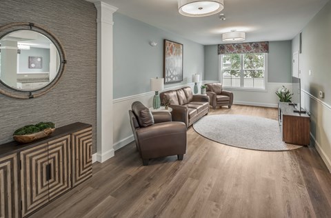 a living room with leather furniture and a rug at Eden & Main 55+ Apartments, Southington