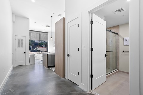 a hallway with white doors and a stainless steel floor with a kitchen in the background