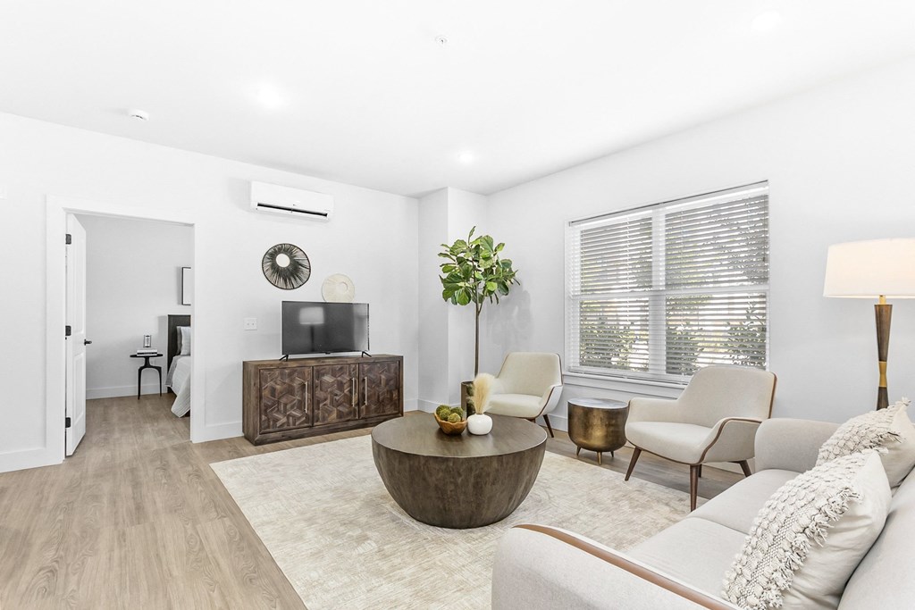 A living room with a white couch, a wooden coffee table, and a television.