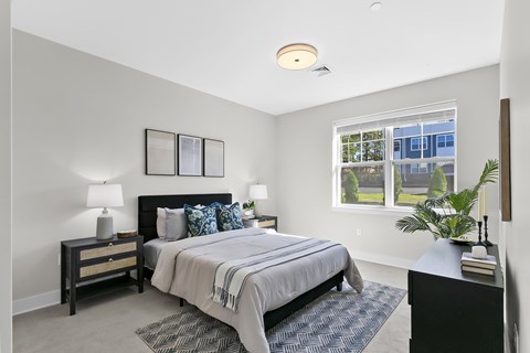 A bedroom with a bed, nightstand, and window.